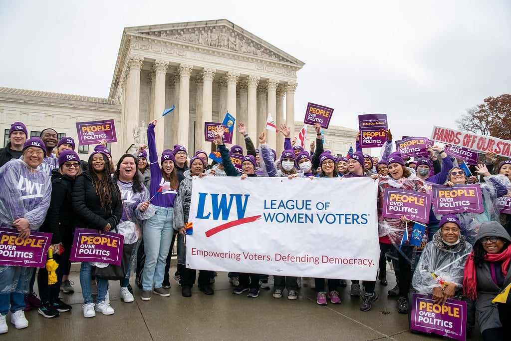 LWV staff in front of the Supreme Court holding a League banner