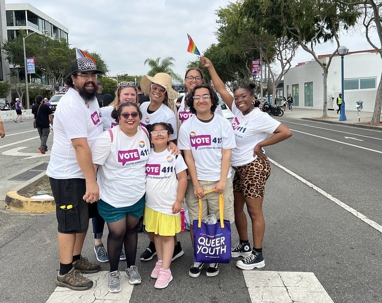 A group of people in VOTE411 shirts, one of whom is holding a rainbow Pride flag