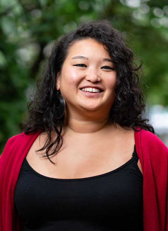 Headshot of Adena Ishii in a red jacket in front