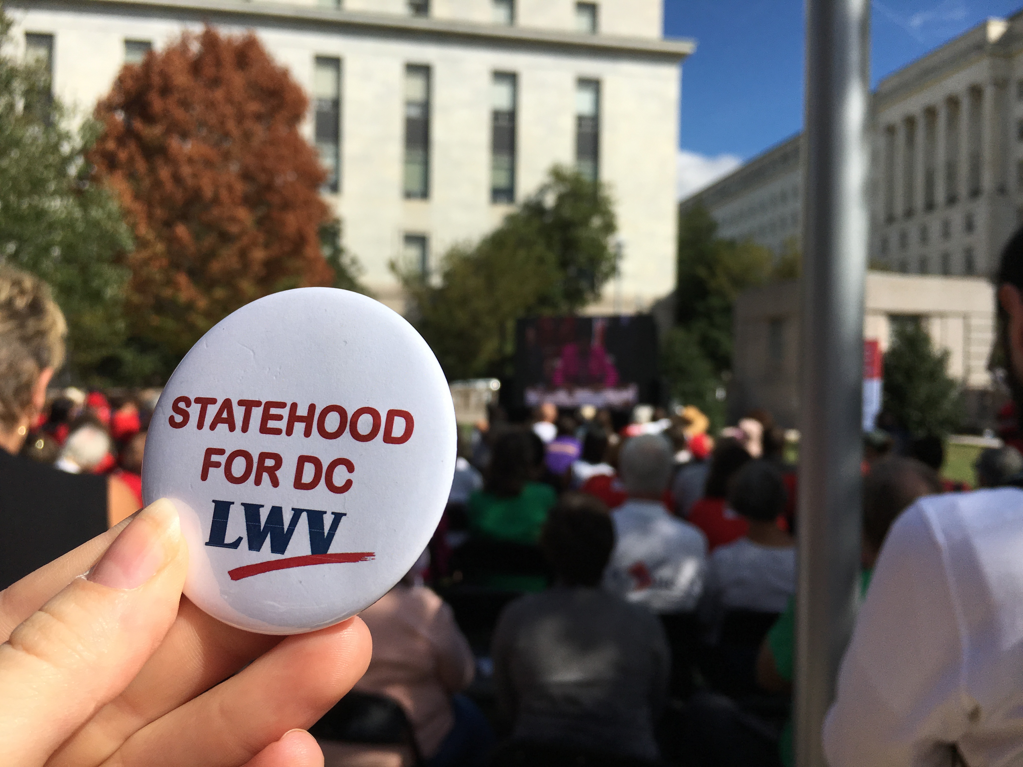 A person holding a button that says "Statehood for DC"