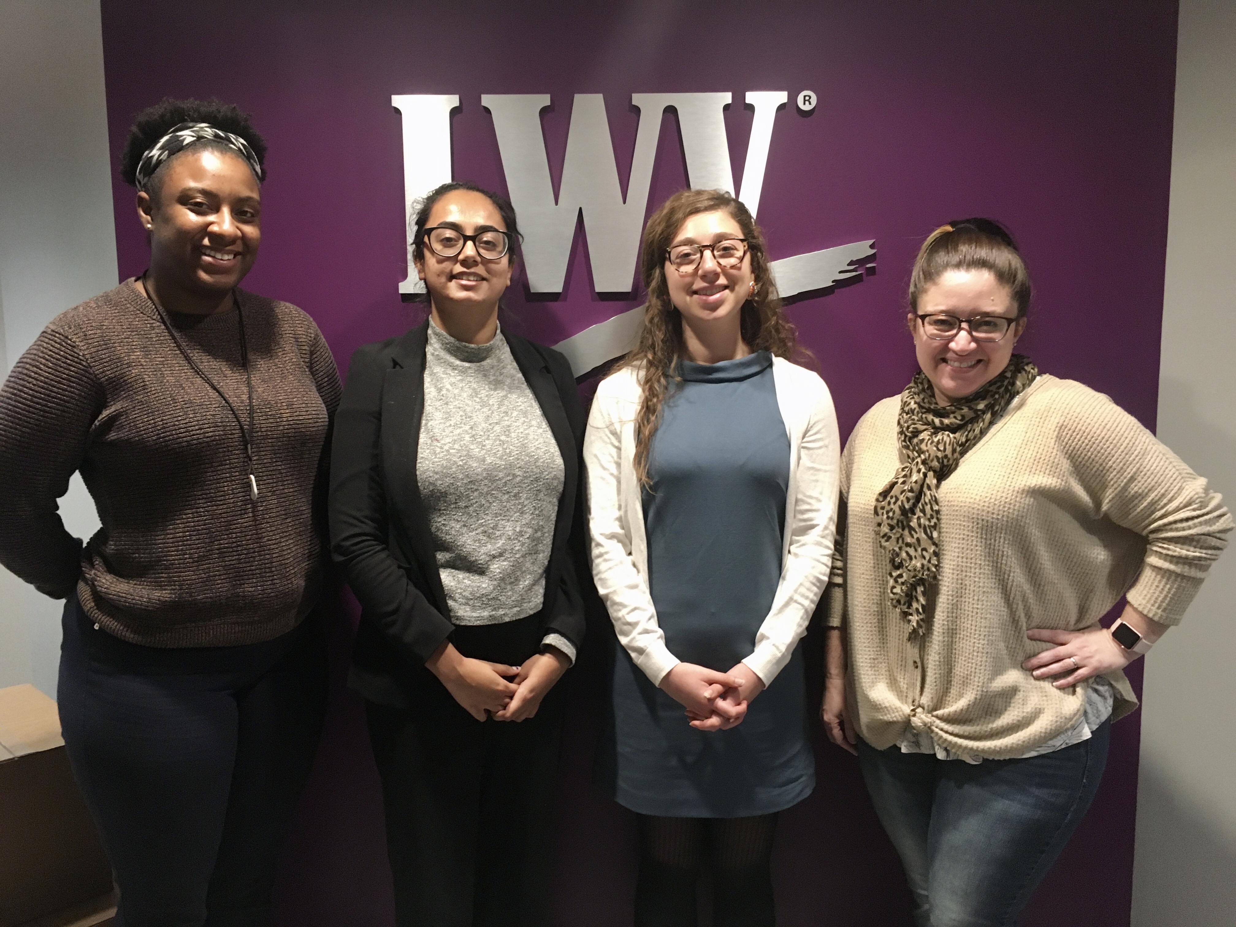 Four women posing in front of an LWV banner