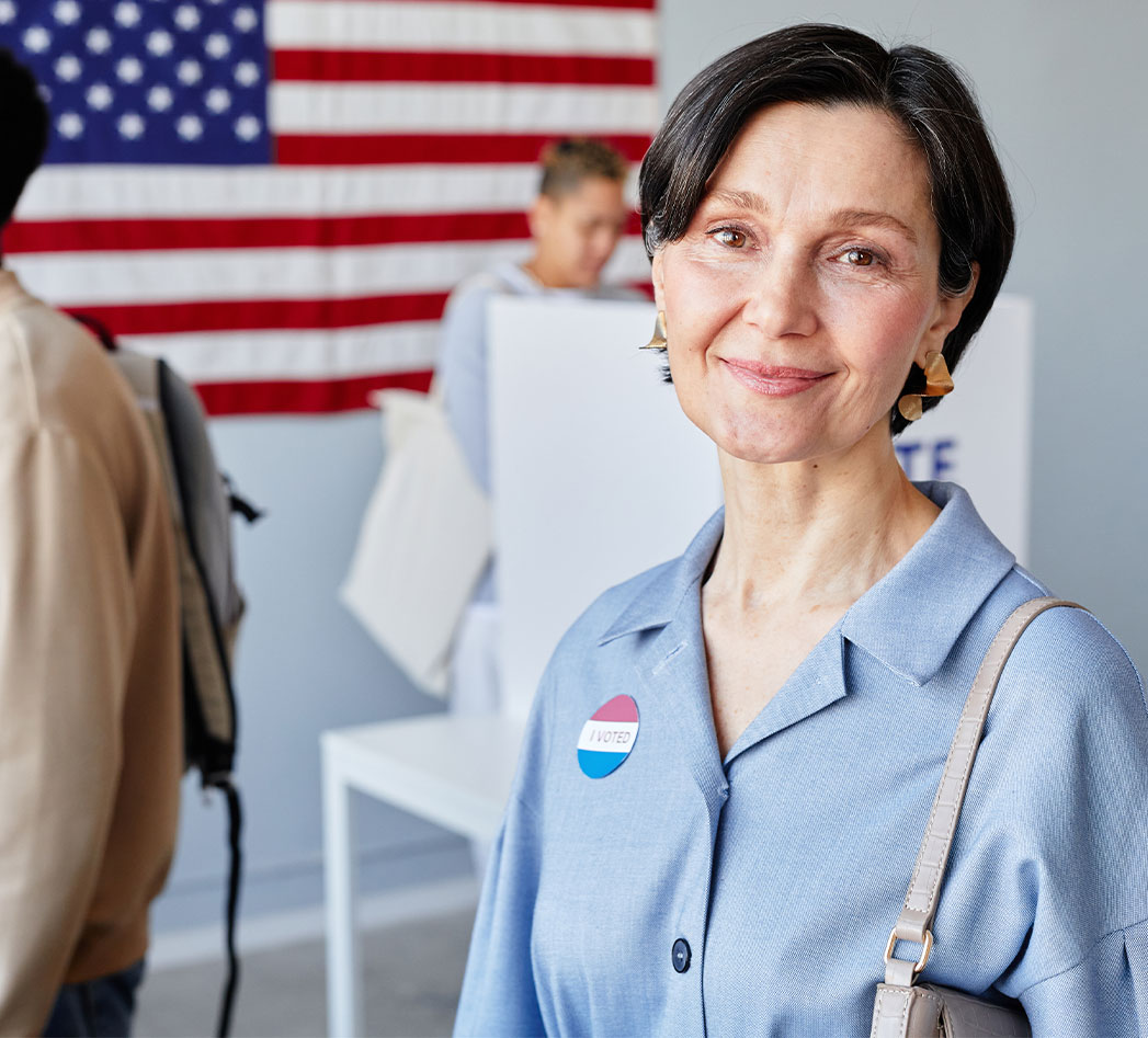 A woman smiling in front of an American flag