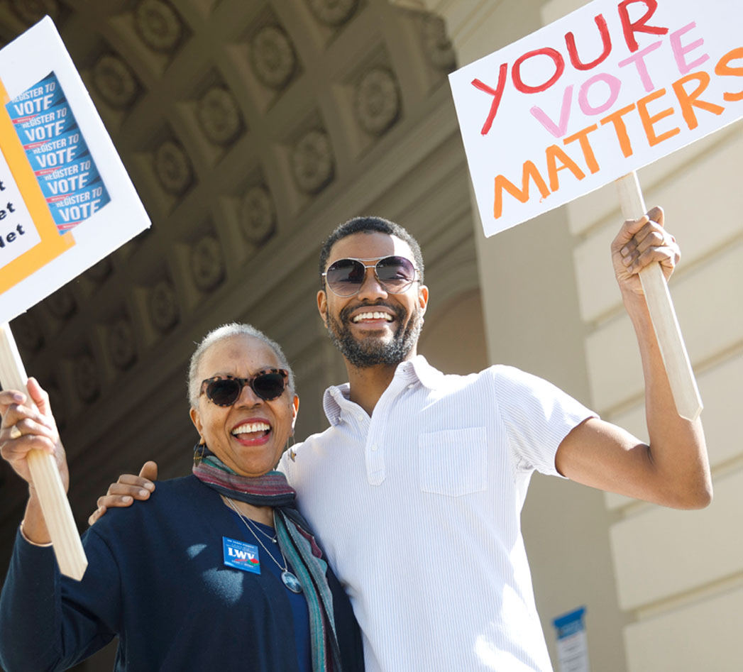 Two people holding signs, one says "Your Vote Matters"