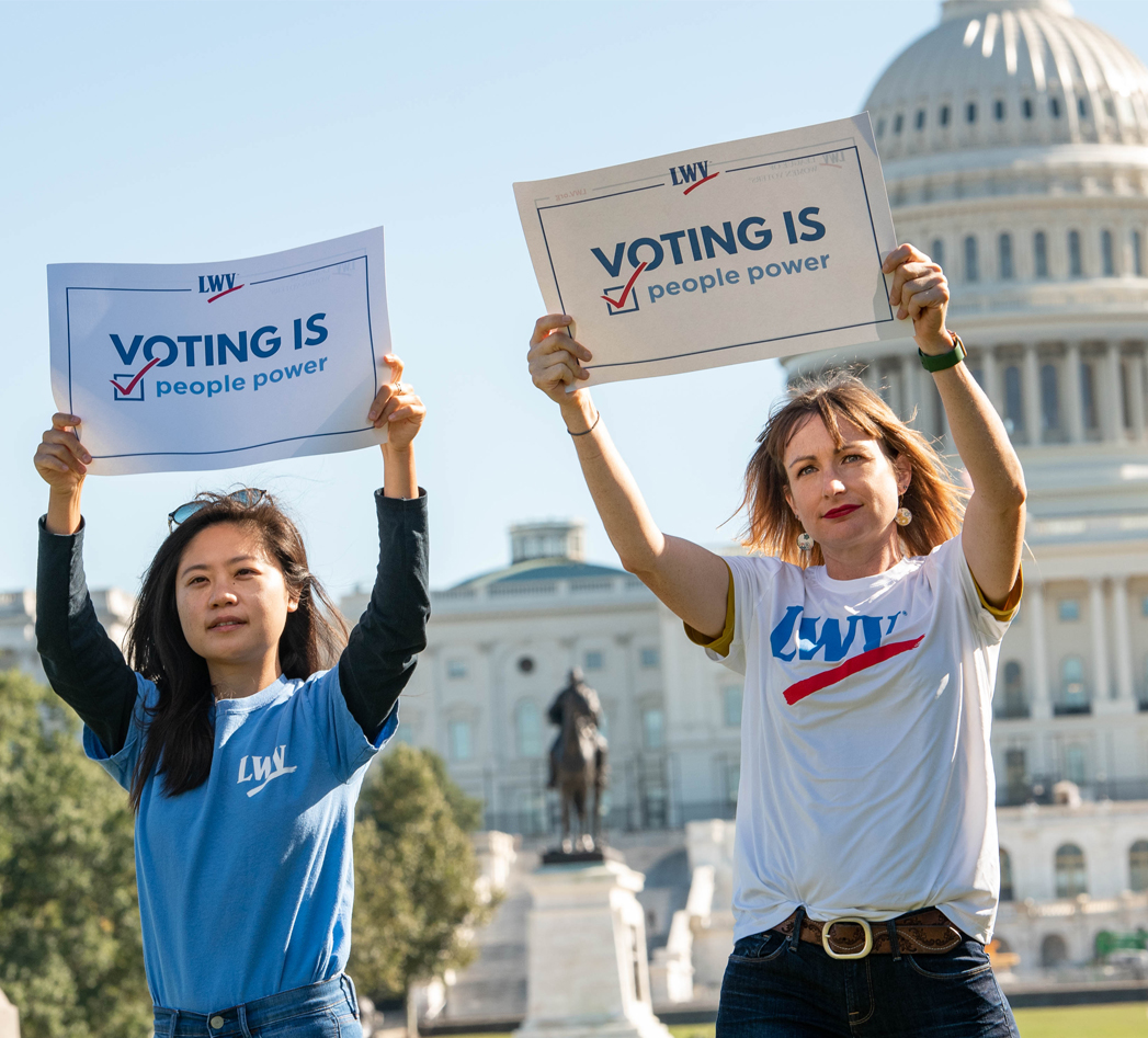 Women holding signs saying "Voting is People Power" in front of the US Capitol