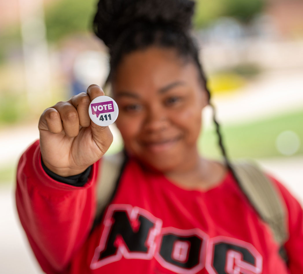 Young woman holding a VOTE411 pin