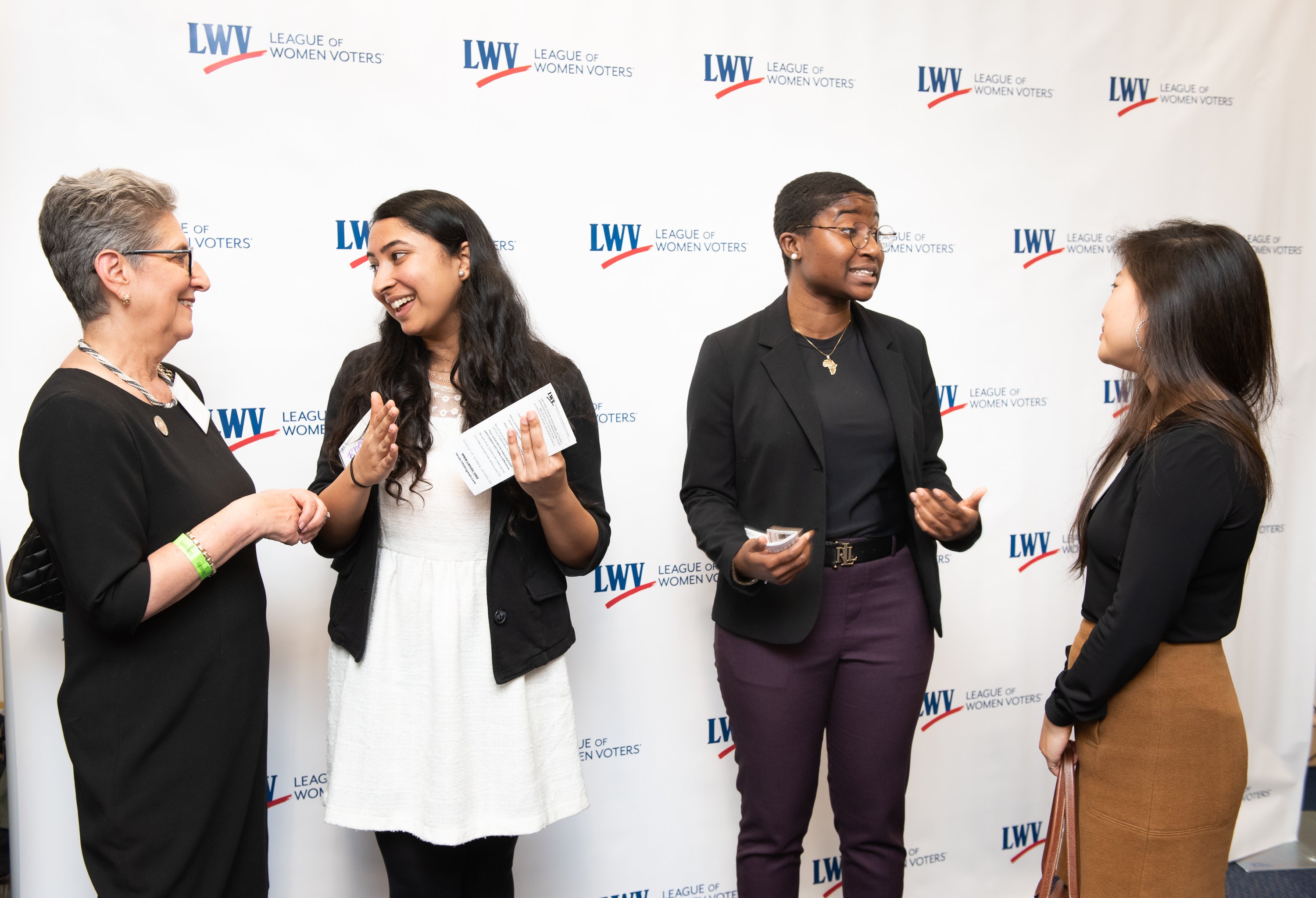 Four women speaking in front of a white backdrop