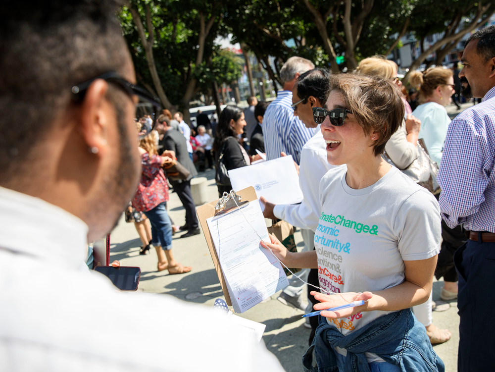 Woman holding up a petition and smiling at a crowd