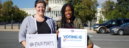 Two women holding #Fairmaps signs in front of Capitol