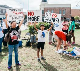 People in a lawn protesting with signs for gun reform