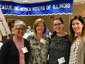 Four women smiling in front of LWV banner