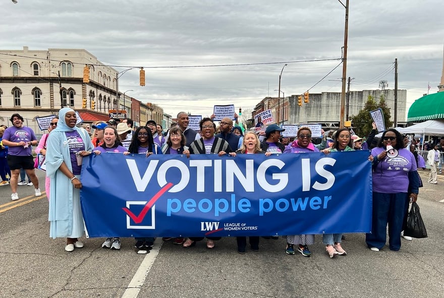 League members holding a "Voting is People Power" banner while marching
