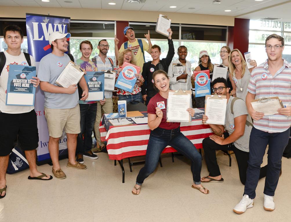 Group of people holding voter registration materials at a booth