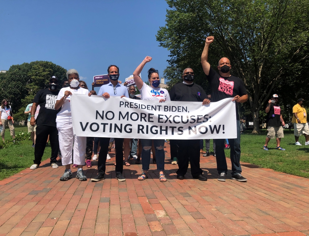 Photo of Dr. Deborah Ann Turner, Rabbi Pesner, Virginia Kase Solomón, Rev. McDonald, and Ben Jealous holding a banner that reads "President Biden, No more excuses: Voting Rights Now!"