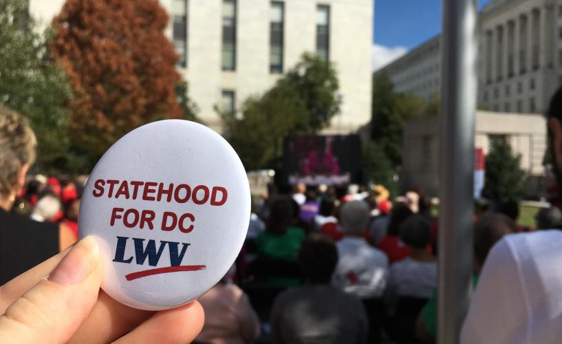 A person holding a button that says "Statehood for DC"