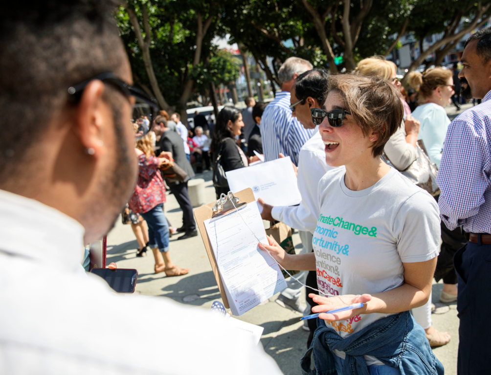 Woman holding up a petition and smiling at a crowd