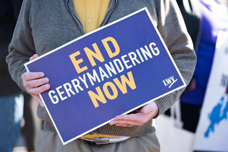 Person holding a sign that says "End Gerrymandering Now"