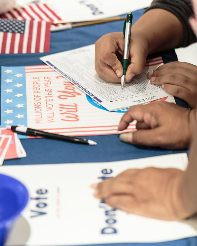 People visible by their hands filling out registration forms