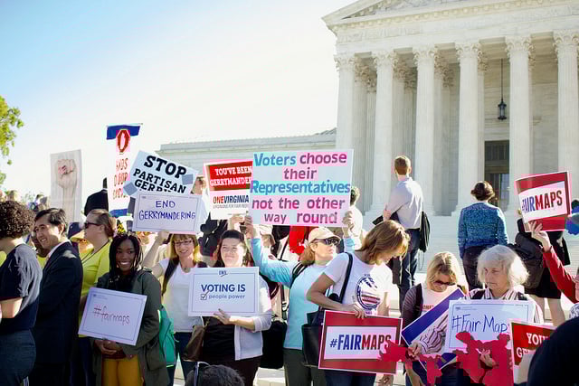 Rally participants stand in front of the Supreme Court with signs demanding fair maps