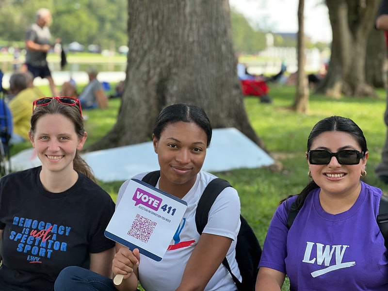 Three women, center woman is holding a VOTE411 sign