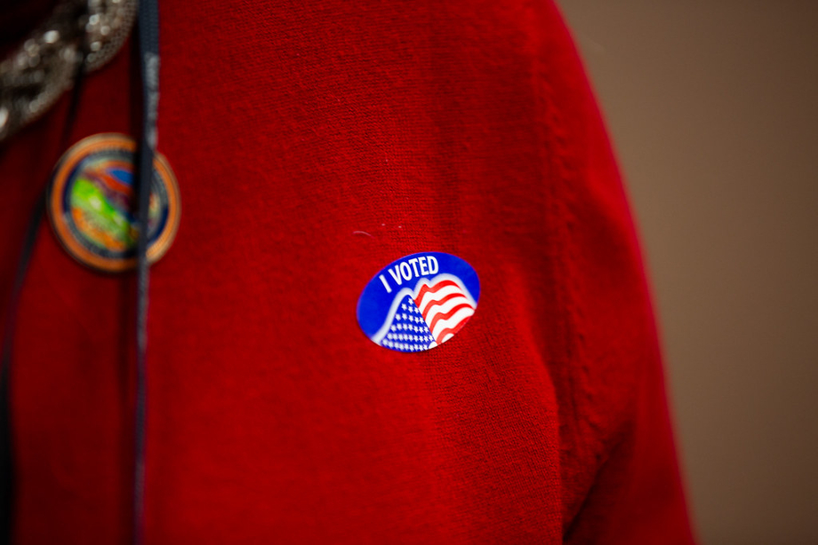 A person in a red jacket with an "I Voted" sticker