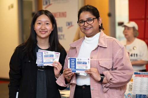 Two women holding up voter registration postcards on National Voter Registration Day