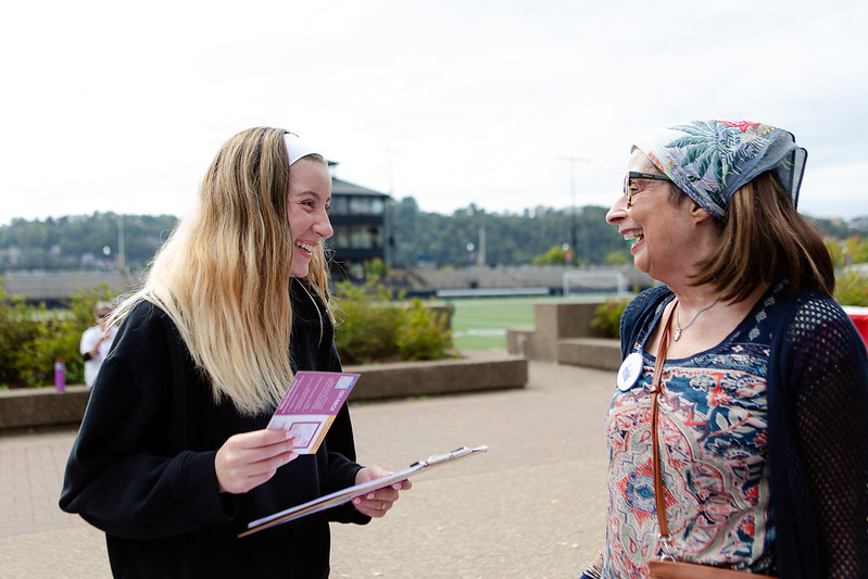 Two women holding voter registration information and talking