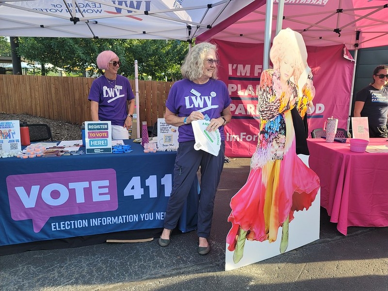 League members at a booth to register voters next to a cutout of Cyndi Lauper