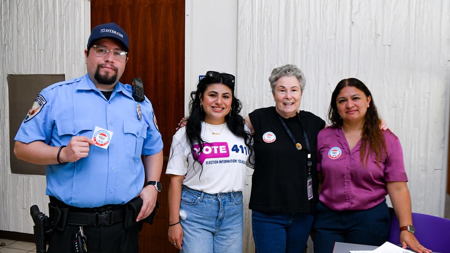 Four people smiling, one holding a NVRD sticker and one in a VOTE411 shirt