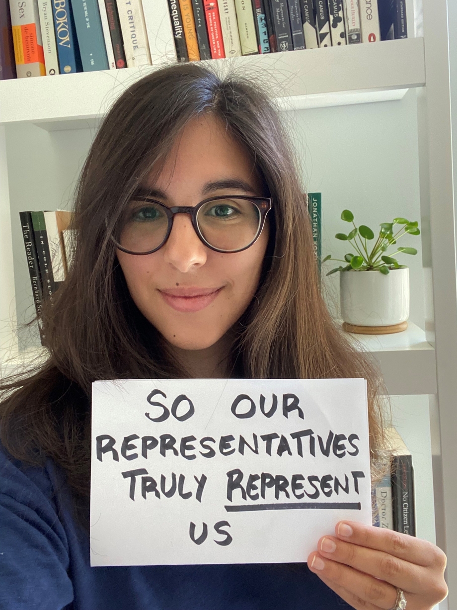 Picture of woman holding up sign that reads "so our representatives truly represent us"