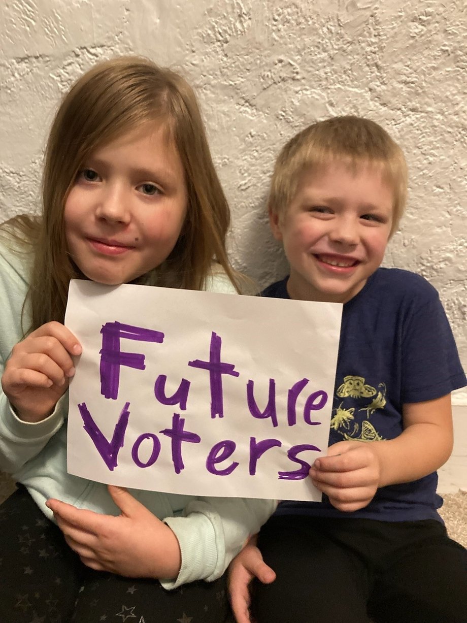 The author's children holding a sign that says "future voters"