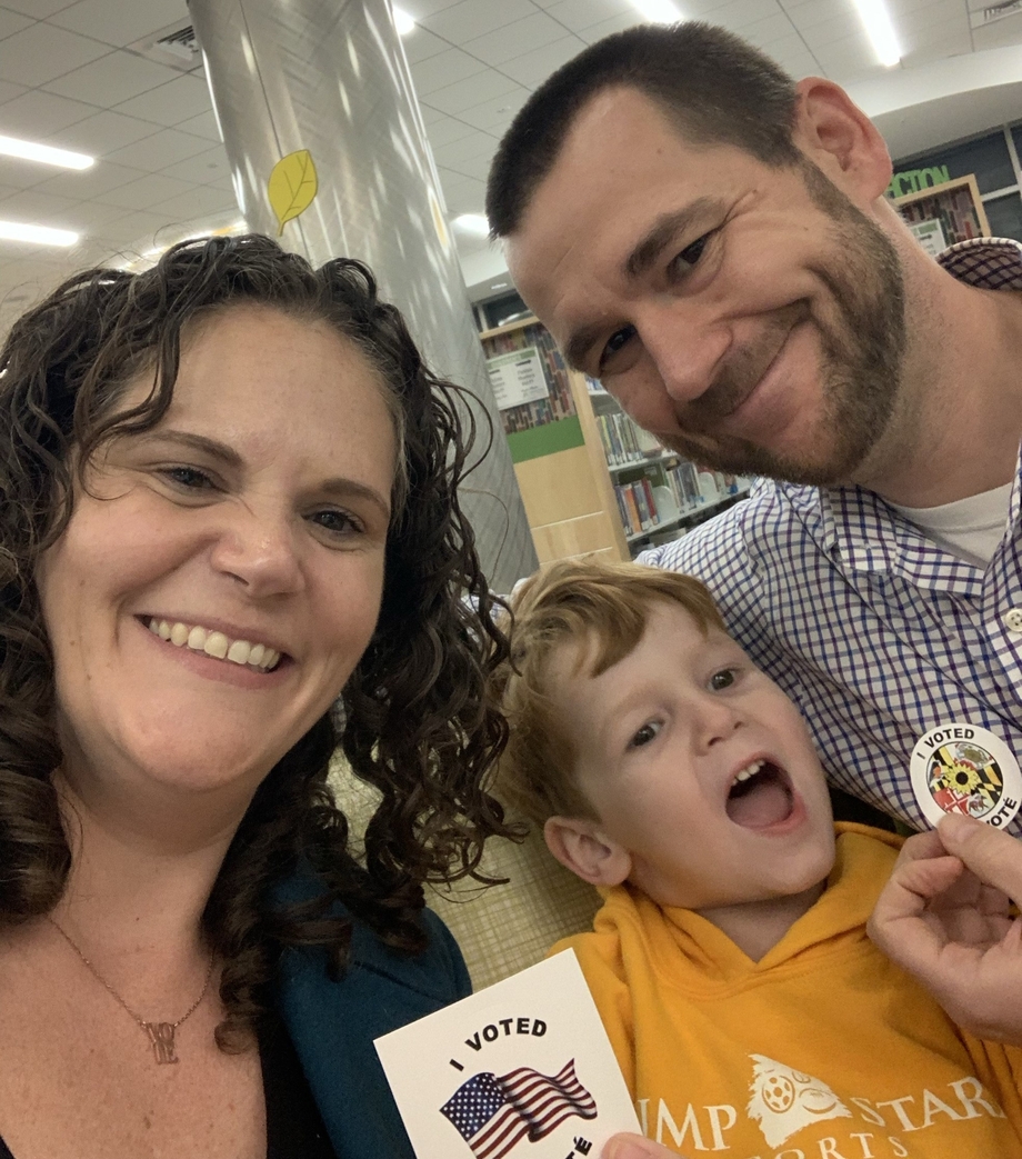 Two parents and a child holding up "I Voted" stickers