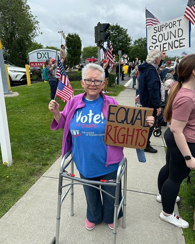 A league member holding a sign that says "Equal Rights" and an American flag