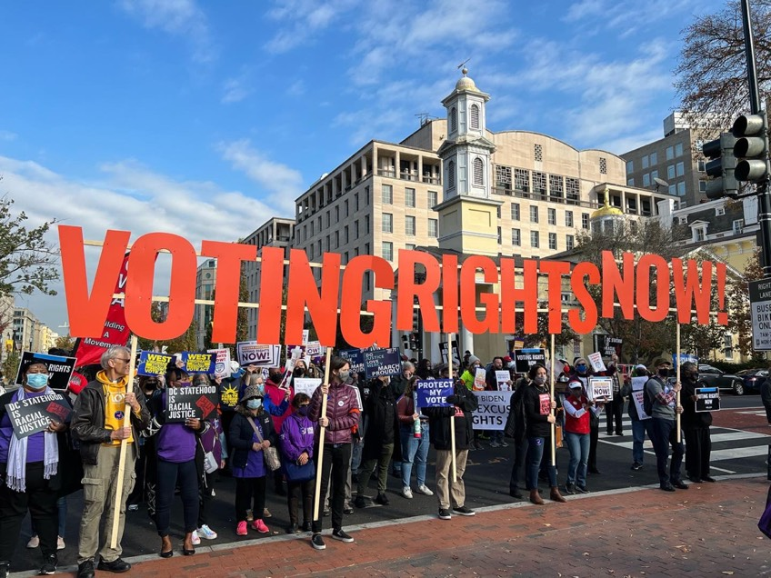 Protestors holding letters that spell out "Voting Rights Now"