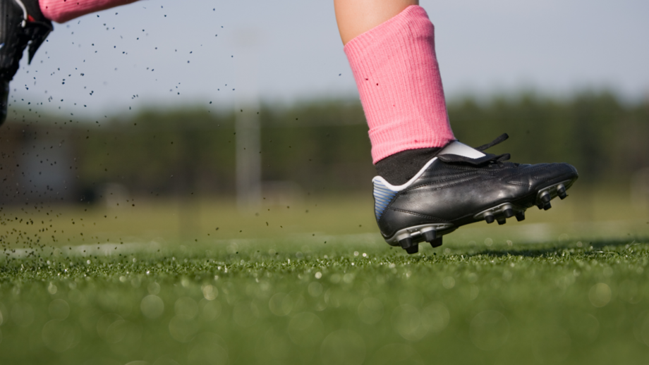 Girl wearing cleats and running through a field