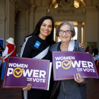 Women holding "Women Power the Vote" signs