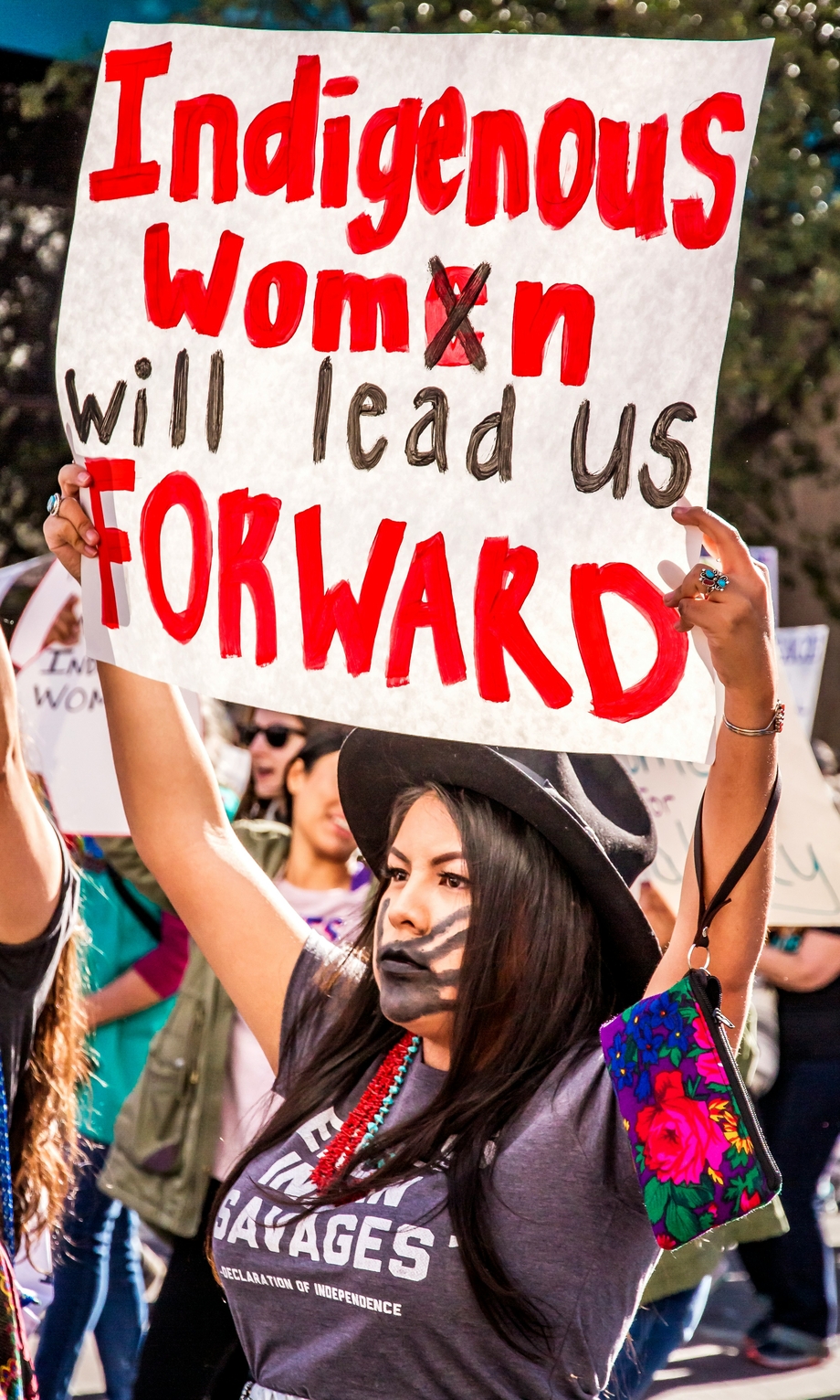 A woman holding a sign saying "indigenous women will lead us forward"