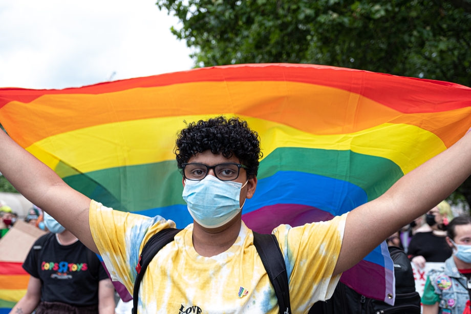A person holding a gay pride flag at a protest