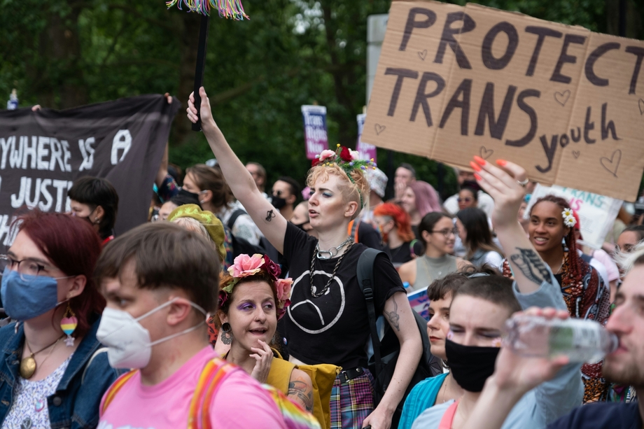 Protestors, one of whom holds a sign that says "protect trans youth"