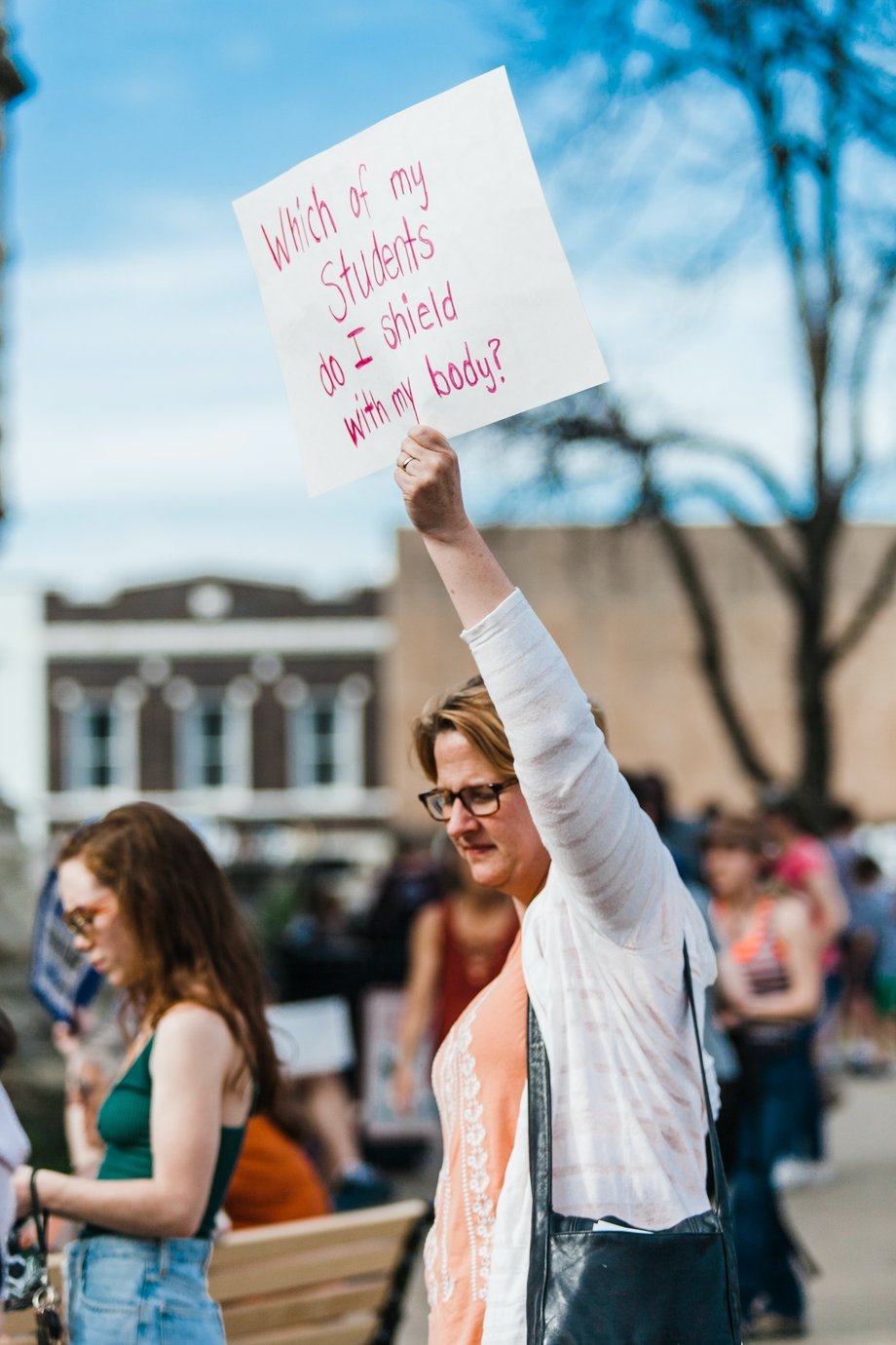 Woman holding a sign saying "which of my students do I protect with my body?" at a gun control protest