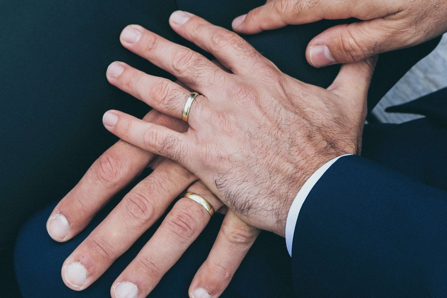 Men holding hands with wedding rings