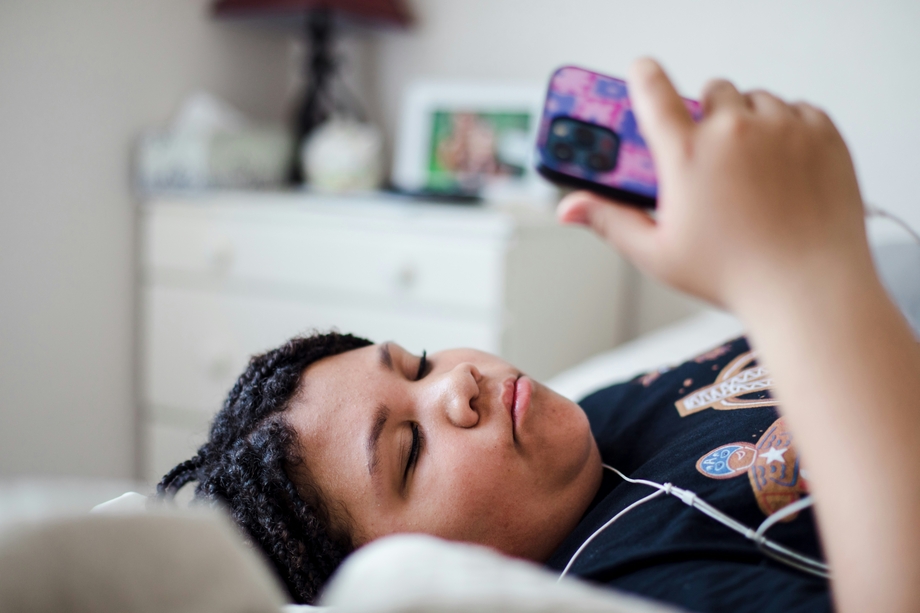 A preteen lying down looking at their phone