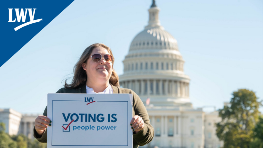 A woman holding a "voting is people powered" sign in front of the US Capitol
